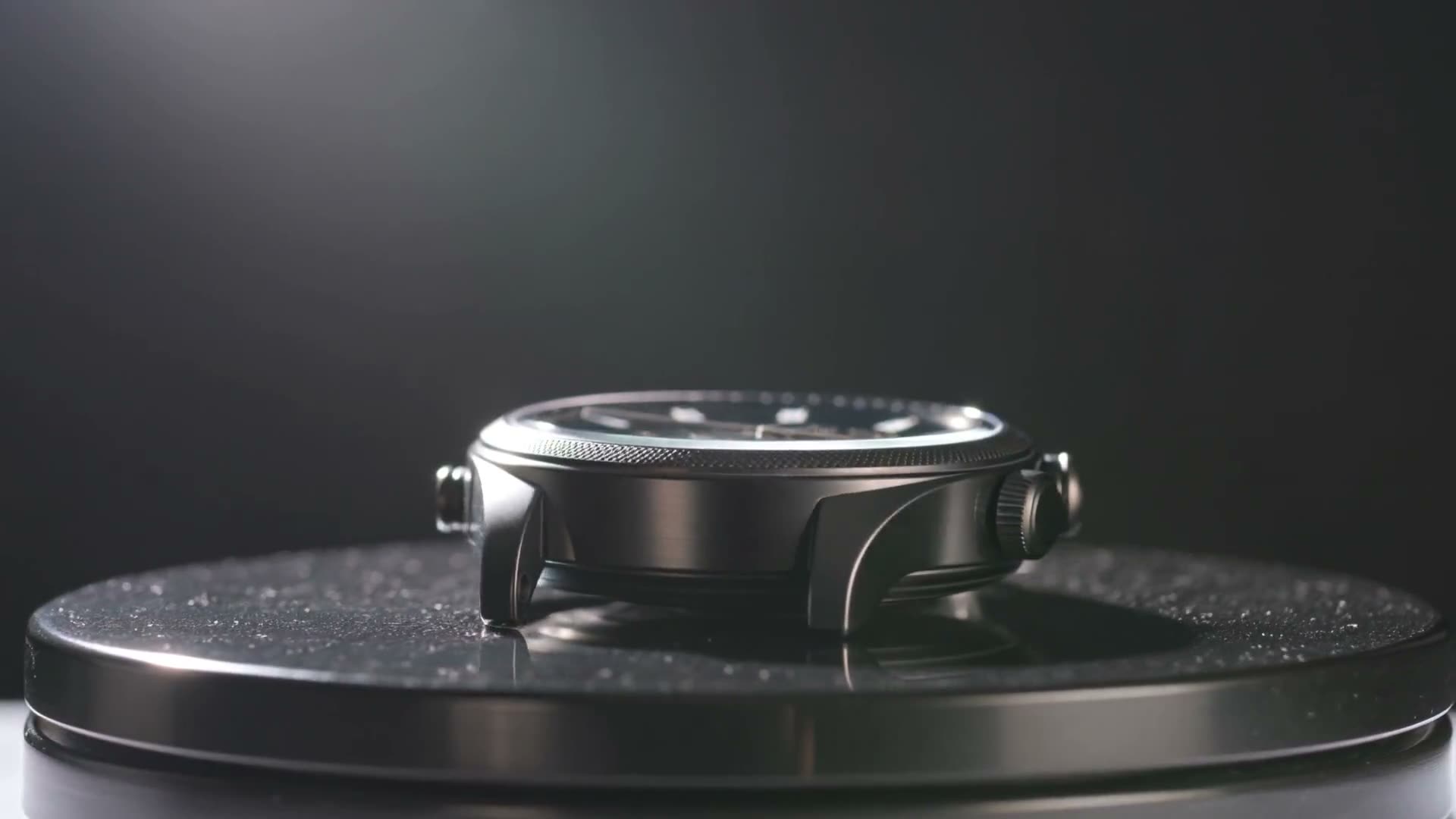 Rotate the stainless-steel watch slowly on a dark plinth, controlled highlights, shallow depth, no text overlays.